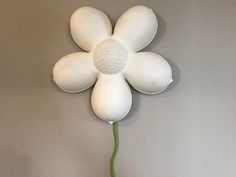 a white flower shaped object hanging on the wall