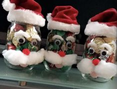 three glass jars with santa hats and eyeballs on them sitting on a shelf in front of a mirror