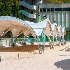 a row of white umbrellas sitting next to each other on top of a sandy beach