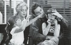 a black and white photo of three people talking on the phone