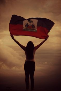 a woman holding a flag in front of a cloudy sky