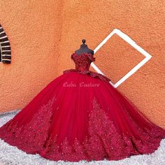 a red ball gown on display in front of an orange wall