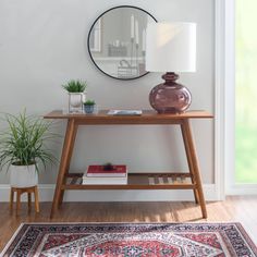 a wooden table topped with a mirror next to a potted plant and a rug