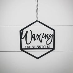 a hanging sign that says waxing in session