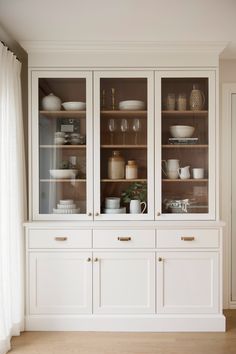 a white china cabinet filled with dishes and cups