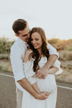 a man and woman hugging each other on the road