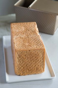 a piece of bread sitting on top of a white plate next to an empty box