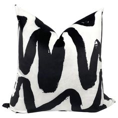 a black and white pillow with an abstract design on the front, sitting against a white background