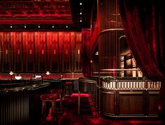 a dimly lit bar with red curtains and stools