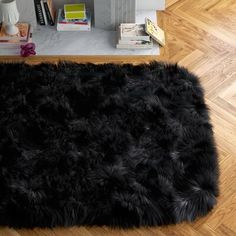 a black shaggy rug on the floor in front of a bookshelf and bookcase