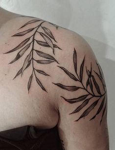 a close up of a person's shoulder with leaves on it and the top half of his arm