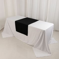 a black and white table cloth is on top of a rectangular table with two square tables