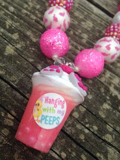 a necklace with pink and white beads hanging from it's end on a wooden table