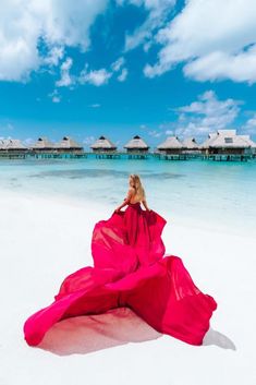 a woman in a red dress on the beach