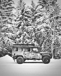 an old jeep is parked in front of some snow covered trees on a snowy day