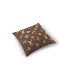 a brown and white pillow with louis vuitton pattern on the front, sitting on top of a white surface