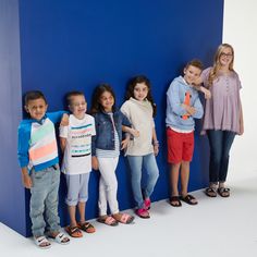 a group of children standing in front of a blue wall