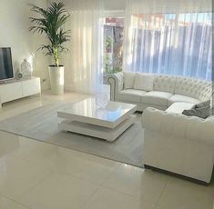 a living room with white furniture and a flat screen tv