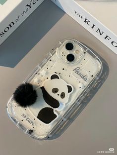 a cell phone case with a panda bear design on the front and bottom, sitting next to a box