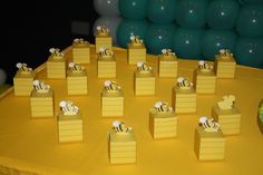 there are many small boxes that have bees on them, sitting on a table with balloons in the background