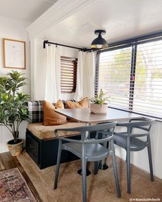 a living room with a couch, table and chairs next to a potted plant