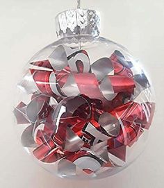 a glass ornament filled with red and silver ribbons