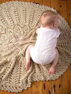 a baby laying on top of a crocheted rug