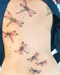 a woman's back with three dragonflies on it