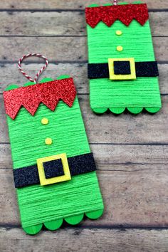 two christmas decorations made out of paper on a wooden table with red and green glitters