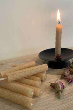 a lit candle sitting on top of a wooden table next to dried flowers and candlesticks