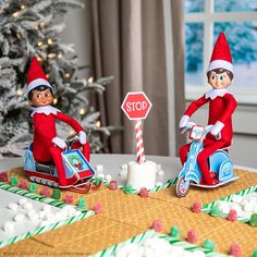 two elf figurines sitting on top of a table next to a stop sign