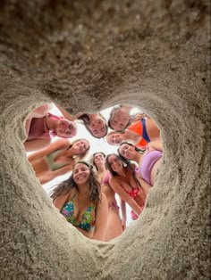 a group of women standing in the middle of a heart shaped hole with their hands together