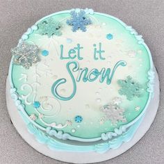 a frosted cake with snowflakes and let it snow written on the top