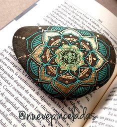 a rock with a flower painted on it sitting on top of an open bible book