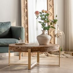 a vase with flowers on a table in front of a couch and mirror behind it