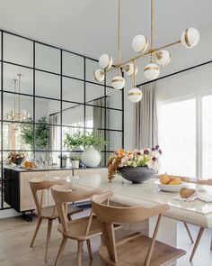 a dining room table with chairs and a bowl of fruit on it in front of a large mirror