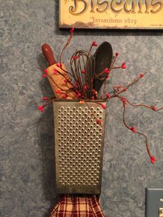 a kitchen utensil holder with spoons and red berries in front of a sign