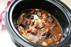 a slow cooker filled with meat and vegetables