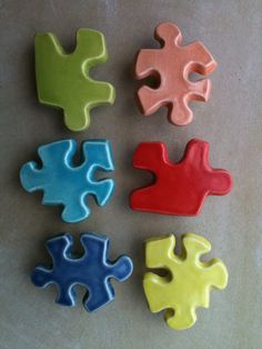 four pieces of colorful puzzle sitting on top of a white countertop next to each other