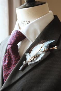 a man wearing a suit and tie with a feather brooch on his lapel