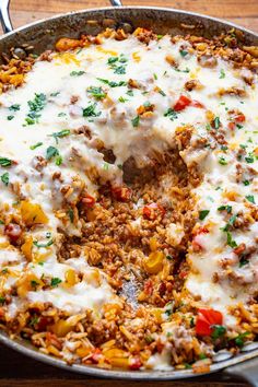 a casserole dish with meat and cheese in it on a wooden table next to utensils