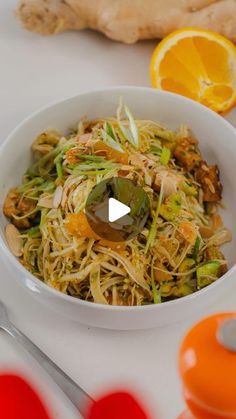 a white bowl filled with food next to an orange and some utensils on a table