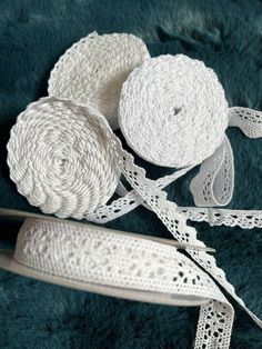 two rolls of white twine sitting on top of a green blanket next to scissors