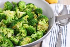 a bowl filled with broccoli sitting on top of a table next to a fork