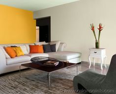 a living room filled with furniture next to a wall painted in yellow and orange colors