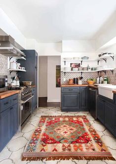 a rug in the middle of a kitchen with blue cabinets and counter tops, along with an area rug on the floor