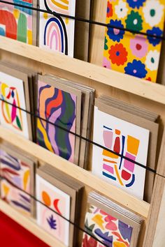 several colorful paintings are displayed on wooden shelves