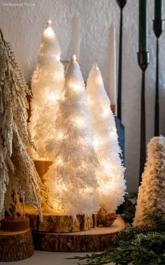 three white christmas trees with lights on them