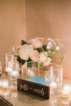 a table topped with candles and vases filled with flowers next to a glass box