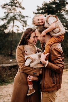 a man and woman holding two children in their arms while they smile at each other